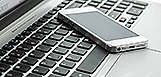 A smart phone on top of a laptop